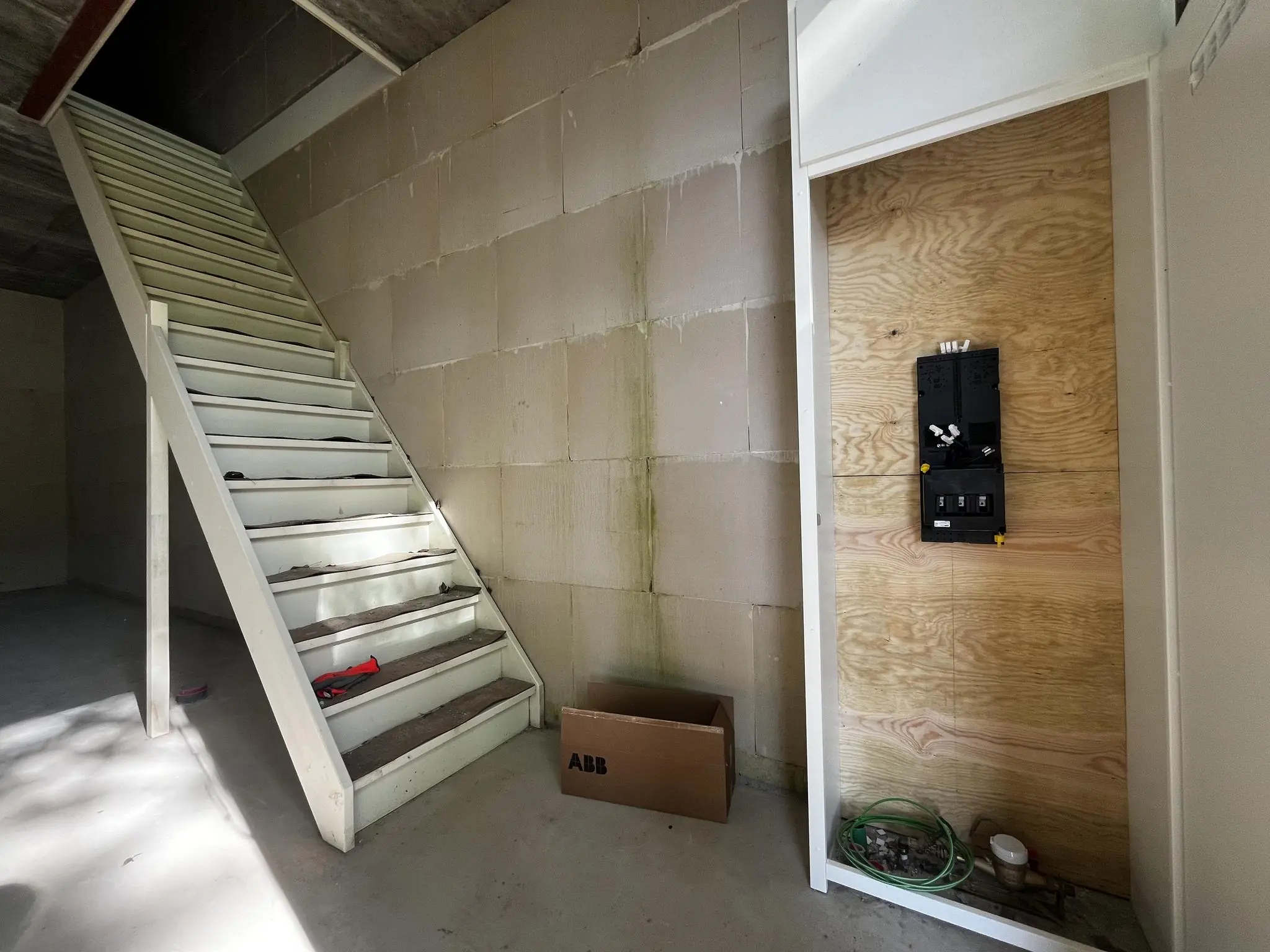 Beginnende elektrische installatie naast een witte trap in een casco nieuwbouwwoning aan de Broekdijk West.